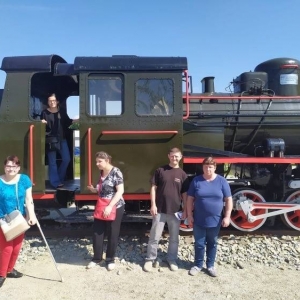 Na zdjęciu widać pięciu osób przy zabytkowej starej lokomotywie