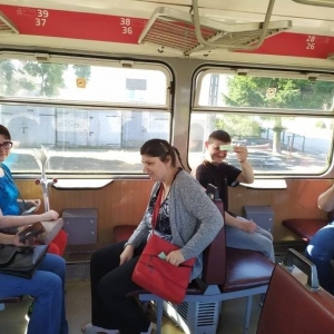 Na zdjęciu widać 5 osób siedzących w kolejce wąskotorowej pokazujących bilety