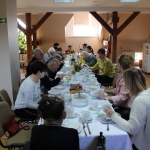 Na zdjęciu widać stół, przy którym siedzą uczestnicy śniadania wielkanocnego